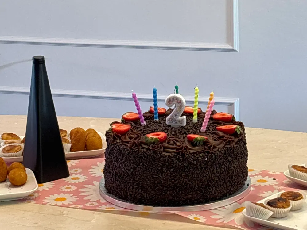 Birthday: chocolate cake with colorful candles and the number 2, surrounded by sweets